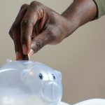 person putting coin in a piggy bank