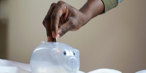 person putting coin in a piggy bank