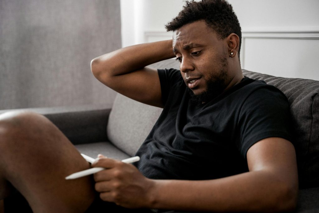 man in black crew neck t shirt sitting on gray couch