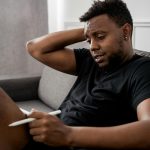 man in black crew neck t shirt sitting on gray couch