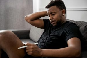 man in black crew neck t shirt sitting on gray couch