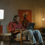 man sitting on an armchair while using his laptop