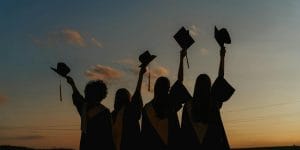 silhouette of people raising their graduation hats